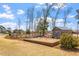 Expansive backyard with a wooden deck, shed, trees, and fencing under a partly cloudy blue sky at 12 Beacon Ridge Blvd, Chapel Hill, NC 27516