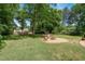 Spacious backyard featuring lush grass, mature trees, and a gravel area with a fire pit at 1274 Candlewood Dr, Elon, NC 27244