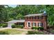 Charming red brick home featuring a well-manicured lawn, mature trees, and classic black shutters at 1274 Candlewood Dr, Elon, NC 27244