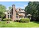 Beautiful brick home with a covered patio, a chimney, green grass, mature trees, and large windows at 1312 Glenden Falls Way, Raleigh, NC 27614