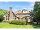 Exterior of a brick home featuring a chimney, large windows, well-kept lawn, covered patio, and beautiful landscaping at 1312 Glenden Falls Way, Raleigh, NC 27614