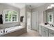 Elegant bathroom with a soaking tub under an arched window and a separate vanity area at 1312 Glenden Falls Way, Raleigh, NC 27614
