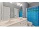 Well-lit bathroom featuring a double sink vanity, white cabinetry, and a shower with blue shower curtain at 1312 Glenden Falls Way, Raleigh, NC 27614