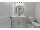 Stylish half bathroom featuring a round mirror and a modern vanity with hardware at 1430 Clifton Pond Rd, Louisburg, NC 27549