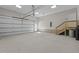 Spacious garage with stairs leading to additional storage, automatic door, and neutral colored walls at 1430 Clifton Pond Rd, Louisburg, NC 27549