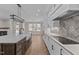 Open kitchen with white cabinets, marble countertops, stainless appliances and wood floors open to living area at 1430 Clifton Pond Rd, Louisburg, NC 27549