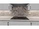 Close-up of the kitchen backsplash and cooktop with white countertops and shaker cabinets at 1430 Clifton Pond Rd, Louisburg, NC 27549