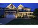 Inviting home exterior with a two-car garage and a cozy front porch, illuminated beautifully at twilight at 155 Annabelle Branch Ln, Apex, NC 27523