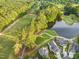 An aerial view captures homes nestled beside a golf course and tranquil lake surrounded by lush green trees at 17 Nicklaus Way, Clayton, NC 27520