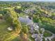 An aerial view captures community homes by a scenic lake and lush golf course, surrounded by lush trees at 17 Nicklaus Way, Clayton, NC 27520