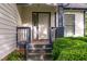 Covered front porch with classic white door, dark trim, and manicured shrubs at 17 Nicklaus Way, Clayton, NC 27520