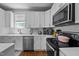 A modern kitchen featuring white cabinets, quartz countertops, stainless appliances, and a black electric range at 2003 Wa Wa Ave, Durham, NC 27707