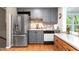 Renovated kitchen featuring stainless steel fridge, gray cabinets, and warm wood floors at 204 Random Ln, Burlington, NC 27215