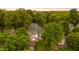Aerial view of a green roofed two-story home nestled among lush trees in a serene neighborhood at 223 Hall Ave, Burlington, NC 27217