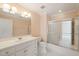 Bright bathroom with white vanity, sink, toilet, and a glass-enclosed shower and tub at 2303 Upper Oaks Way, Raleigh, NC 27615