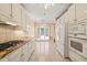 Well-lit kitchen with white cabinetry, stainless appliances, gas range, and a view of the outdoor patio at 2303 Upper Oaks Way, Raleigh, NC 27615