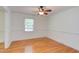 Cozy bedroom featuring hardwood floors, a ceiling fan, and plenty of natural light from the large window at 4300 Edgehill Ct, Raleigh, NC 27612