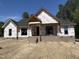New construction home featuring a brick foundation, black windows, and architectural roof against a clear blue sky at 5021 Mitchell Town Rd, Youngsville, NC 27596