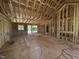 Unfinished living room showcasing wood framing, large windows, and an open-concept design during construction at 5021 Mitchell Town Rd, Youngsville, NC 27596