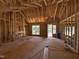 Unfinished living room showcasing wood framing, large windows, and an open-concept design during construction at 5021 Mitchell Town Rd, Youngsville, NC 27596