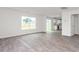 Bright living room featuring gray LVP flooring, a large window, and open access to the modern kitchen at 525 Lochalsh Dr, Gibsonville, NC 27249