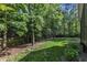 Landscaped backyard featuring a grass lawn, mature trees, a wooden fence, and garden areas at 5600 Bennettwood Ct, Raleigh, NC 27612