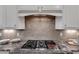 Close-up of the kitchen featuring a modern stovetop with gray backsplash and granite countertops at 5600 Bennettwood Ct, Raleigh, NC 27612