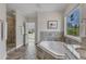 Well-lit bathroom with a soaking tub, shower, and large window overlooking trees at 5600 Bennettwood Ct, Raleigh, NC 27612
