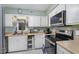 Bright kitchen features white cabinetry, stainless steel appliances, and marble-style floors at 629 Pine Ridge Pl, Raleigh, NC 27609