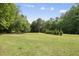 Expansive backyard featuring mature trees and a level grassy area at 7116 Incline Dr, Wake Forest, NC 27587