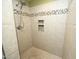 Close up of a tiled shower with a built-in mosaic tile accent stripe and tiled shelving at 74 Pedernales Dr, Smithfield, NC 27577
