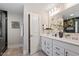 A stylish bathroom has a double vanity, white cabinets, black hardware, and a glass-enclosed shower and a door at 7729 Calcutta Dr, Willow Springs, NC 27592