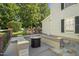 Backyard with a stone patio, built-in benches, and a modern fire pit surrounded by lush greenery at 8524 Society Pl, Raleigh, NC 27615