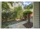 Landscaped backyard with stone walkway leading to a black metal gate and mature shrubbery at 8524 Society Pl, Raleigh, NC 27615