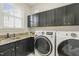 Well-equipped laundry room with sleek black cabinets, granite countertops, and modern washer and dryer units at 8524 Society Pl, Raleigh, NC 27615