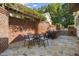 Charming stone patio with brick accents, a dining table, and a built-in grill for outdoor entertaining at 8524 Society Pl, Raleigh, NC 27615
