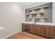 A stylish bar area featuring walnut cabinets, floating shelves with lighting, and a beverage cooler for elegant entertaining at 9004 Meadow Pointe Ct, Wake Forest, NC 27587