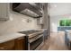 Close up of the gas range with a black range hood and white backsplash in a modern kitchen at 9004 Meadow Pointe Ct, Wake Forest, NC 27587