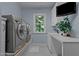 Functional laundry room with modern washer and dryer, sink, cabinets, and outside view at 901 Edgewater Dr, Garner, NC 27529