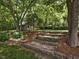 Landscaped backyard featuring a charming shed with stone steps and mature trees at 967 Bynum Rd, Pittsboro, NC 27312