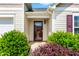 Close-up of the front door, framed by vibrant green shrubs and colorful foliage at 1004 Gold Cir, Mebane, NC 27302