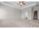 Spacious main bedroom with carpet, ceiling fan, tray ceilings, and access to the bathroom and staircase at 105 Seminole Fields Dr, Broadway, NC 27505