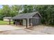 Garage and carport exterior with gray siding, stone accents, and mature trees at 109 Rustler Rd, Louisburg, NC 27549