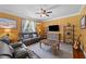 Cozy living room with yellow walls, grey sofas, hardwood floors, and a ceiling fan for added comfort at 109 Rustler Rd, Louisburg, NC 27549