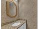Elegant powder room features a granite countertop, oval sink, gold-framed mirror, and patterned wallpaper at 11944 Appaloosa E, Raleigh, NC 27613