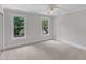 Neutral bedroom with two windows providing natural light, ceiling fan and carpet at 11944 Appaloosa E, Raleigh, NC 27613