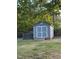 Backyard features a charming shed with painted siding, white trim and doors, perfect for storage at 15 Colonial Hills Dr, Lillington, NC 27546