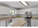 Modern kitchen featuring stainless steel appliances, granite countertops, and white cabinets at 15 Epping Ct, Durham, NC 27703
