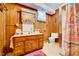 Bathroom with wood paneling, a single vanity, and a walk-in shower with patterned curtain at 206 Kittys Ln, Erwin, NC 28339