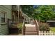 Wooden deck with stairs, railing, and a glimpse of the backyard surrounded by greenery and trees at 209 E Winston St, Youngsville, NC 27596